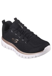 Baskets de sport noires avec tige en mesh, design à lacets et semelle extérieure blanche. Présente des accents métalliques sur le côté et une semelle rembourrée.