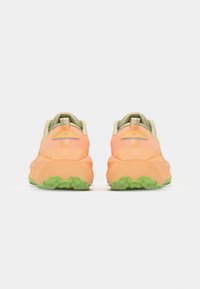 Athletic shoes with a soft orange upper, green rubber sole, and textured back. Features a cushioned collar and dual-color design accents.