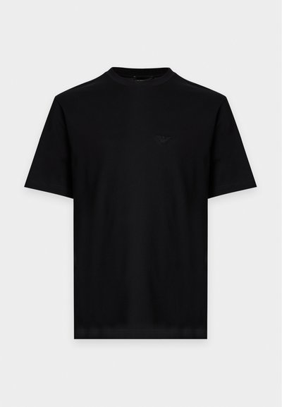 Μαύρο κοντομάνικο T-shirt με στρογγυλή λαιμόκοψη και μικρό ανάγλυφο λογότυπο στην αριστερή πλευρά του στήθους, σε απλό ανοιχτό φόντο.