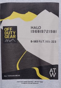 Grå t-shirt med en grafisk design av taggiga berg i svart och gult. Texten inkluderar "OFF DUTY GEAR," "HALO," och "ALL TERRAIN WEAR."