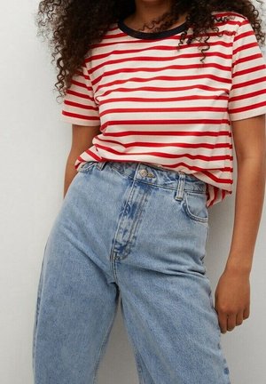 T-shirt en coton à rayures rouges et blanches avec un col foncé, associé à un jean denim bleu clair taille haute avec une coupe classique.