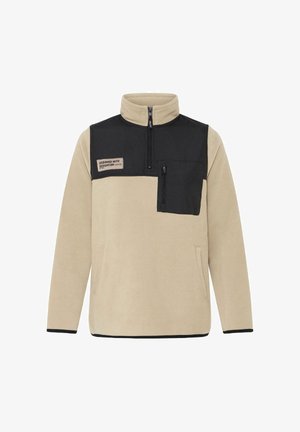 Pull en polaire beige avec un panneau supérieur noir, col zippé à mi-hauteur, poche poitrine zippée et ourlet et poignets noirs contrastants.