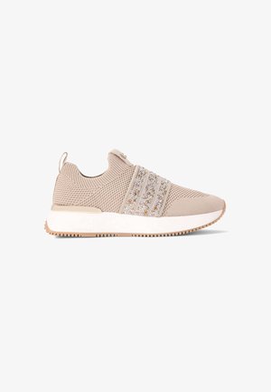 Beige sportieve schoen met bovenwerk van mesh, decoratieve sprankelende banden, gevoerde kraag en een witte zool met een gestructureerd loopvlakpatroon.