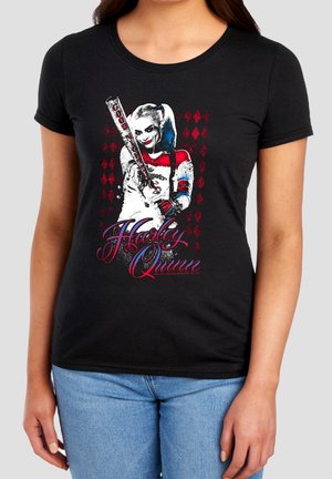 Woman wearing black t-shirt with colorful Harley Quinn holding a baseball bat and red diamond patterns in the background.