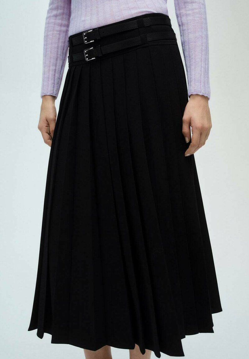 Zwarte plissee rok met twee horizontale stoffen bandjes op de taille, voorzien van zilveren gespen. De stof lijkt glad en ondoorzichtig.