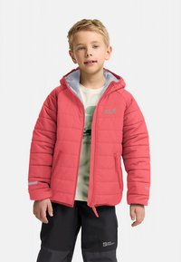 Rød isolasjonsjakke med hette, med grå fôr, vinklet quiltingmønster og en logo på brystet. Brukes med svarte bukser.