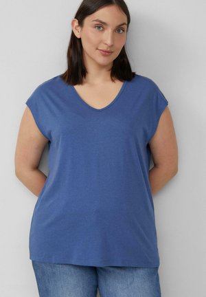 Blaues Baumwoll-T-Shirt mit tiefem V-Ausschnitt und kurzen, kapuzenartigen Ärmeln. Der Stoff wirkt glatt und leicht. Getragen mit hellblauen Jeans.
