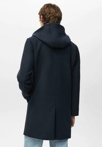 Abrigo de lana azul marino con capucha, de corte recto, mangas largas y una abertura central en la parte trasera para facilitar el movimiento.