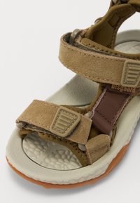 Bruna mocka sandaler med justerbara remmar, texturerad fotbädd, vadderad sula och gummisula. Har en säker och praktisk design.