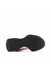 La suela del zapato presenta una superficie de goma negra texturizada con patrones de agarre redondos, destacando un borde lateral liso de color rosa en contraste.