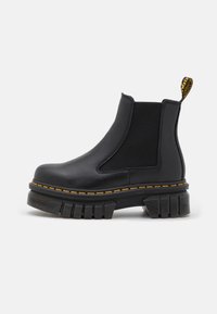 Černá kožená kotníková bota s elastickými bočními panely, silnou podešví a kontrastním žlutým prošíváním. Obsahuje poutko na zadní straně.