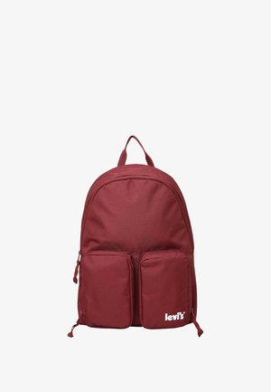 Mochila roja con una textura suave, que cuenta con dos bolsillos frontales y un asa en la parte superior. Logo de la marca en blanco en la parte inferior derecha.