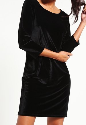 Robe en velours noir avec un col rond et des manches trois-quarts. Le tissu a une texture lisse et une silhouette ajustée.