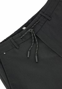 Pantalones negros con cintura elástica, parte delantera plana, cordón ajustable y pequeña etiqueta con logotipo. El material parece suave con un sutil brillo.