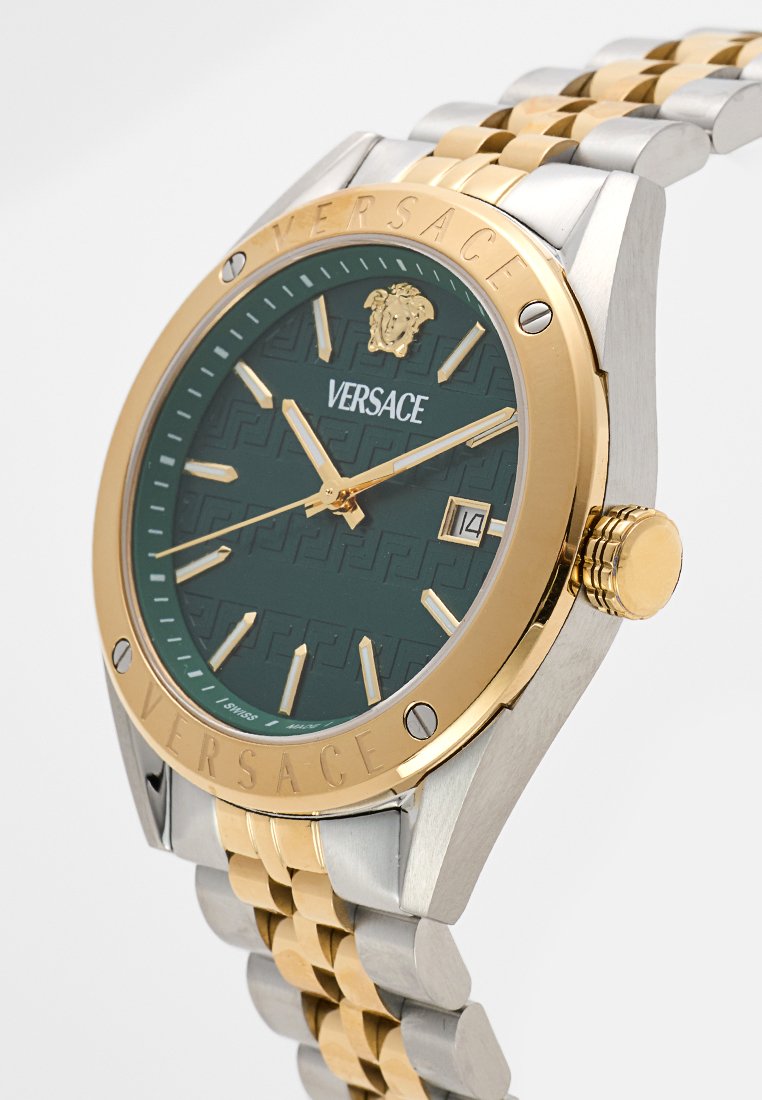 Montre Versace avec un cadran texturé vert, des accents en or, un bracelet en acier inoxydable argent et or, un affichage de la date et un détail de logo.