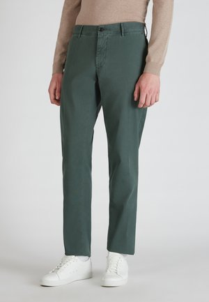 Green cotton trousers with a slim fit, front pockets, button closure, and subtle texture, paired with white sneakers.