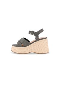 Sandalias de cuña trenzadas en gris con una plataforma texturizada, correas entrelazadas y una correa ajustable en el tobillo. La plataforma está hecha de un material similar al yute.