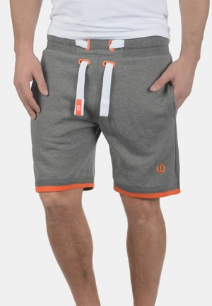 Grå bomulds shorts har en elastisk talje med hvide og orange snore, sidelommer og orange kant ved kanten.