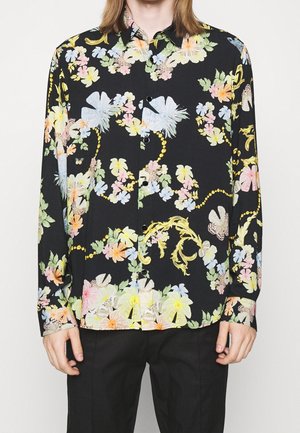 Camicia a maniche lunghe in tessuto nero con un motivo floreale colorato e farfalle; bottoni sul davanti e colletto standard.