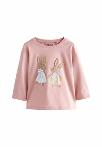 Roze katoenen blouse met lange mouwen, met twee geborduurde konijnen van verschillende texturen, gekleed in lichtblauwe en witte kleding, aan de voorkant.