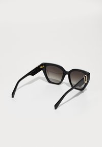 Ochelari de soare negri în stil cat-eye cu lentile gradient, finisaj lucios, accente de hardware aurii pe brațe și un design elegant, unghiular.