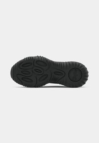 Sorte gummisåler til sneakers med en strukturert, bølgende design med sirkulære riller og hevede mønstre for forbedret grep og fleksibilitet.