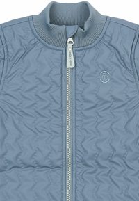 Blaue gesteppte Jacke mit geripptem Kragen, Frontreißverschluss mit der Aufschrift "mikk-line" und kleinem gesticktem Logo auf der linken Brust.