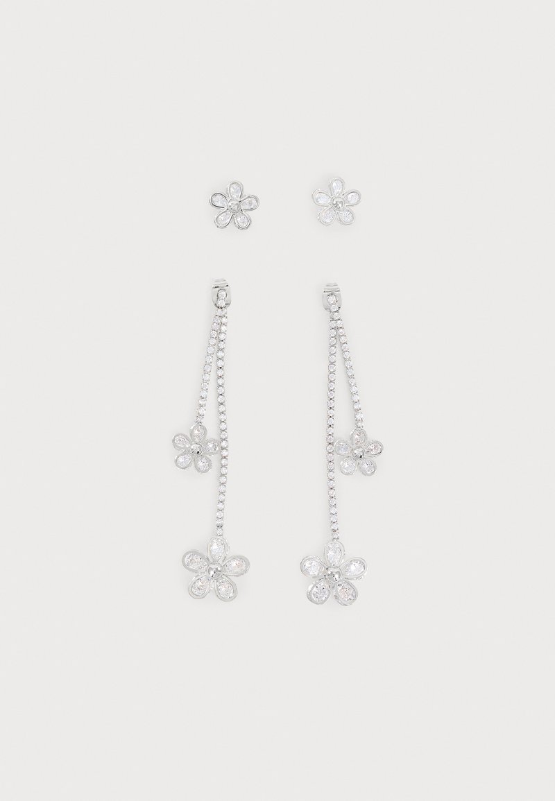 Boucles d’oreilles clous en forme de fleur en argent associées à des boucles d’oreilles pendantes assorties avec deux breloques fleurs sur chaque chaîne.