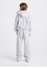 Gray cotton hoodie with a hood, relaxed fit, and ribbed cuffs, paired with matching loose pants featuring an elastic waistband.