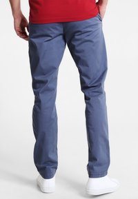 Modré bavlněné kalhoty s volným střihem, s bočními kapsami, mírně zúženými nohavicemi a čistým zakončením na kotnících.