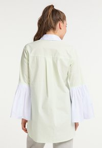 Világoszöld ing fehér harangujjakkal, klasszikus gallérral és hátsó pleats részlettel, sima pamutkeverékből készült.