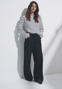 Camisa blanca de manga larga con rayas navy combinada con pantalones anchos navy. Tela suave, corte relajado, con cintura ajustable y bolsillos.