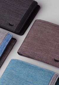 Four wallets displayed on a gray surface: black, dark purple, gray with blue accents, and light blue. The material appears textured fabric.