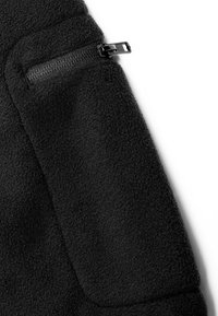 Tissu polaire noir avec une poche zippée horizontale noire partiellement ouverte sur fond blanc.