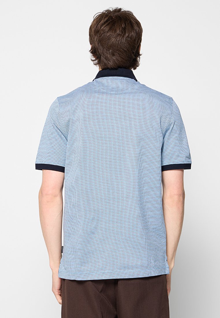 Polo à manches courtes en bleu clair avec un motif texturé, dotée d'un col et de poignets marine. Le dos est simple sans détails supplémentaires.