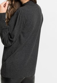 Suéter gris oscuro con cuello redondo, mangas abullonadas y puños y dobladillo acanalados. Fabricado con un material suave y texturizado.