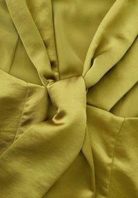 Tissu vert olive avec une texture satinée douce, présentant un détail noué au centre et un design drapé lisse.