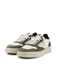 Baskets blanches et vert olive en cuir perforé, avec des lacets plats et des semelles en caoutchouc texturées ; présentent des accents noirs au niveau du talon.