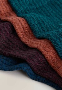 Four layered knit fabrics in deep teal, rust orange, burgundy, and navy. Textured with a ribbed pattern, showcasing soft, cozy wool.