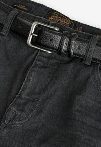 Jeans de mezclilla negros con un cinturón de cuero negro texturizado y hebilla plateada. Incluye detalles de costura y etiqueta de la marca visible en la parte superior.