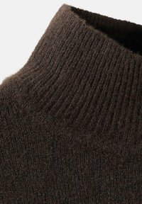 Suéter marrón tejido con cuello alto acanalado, que muestra una textura suave y sutiles variaciones de sombreado a lo largo de la tela.