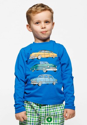 Plava košulja dugih rukava s tri stilizirana vintage automobila u žutoj, zelenoj i svijetloplavoj boji. Zeleni i bijeli karirani hlače.