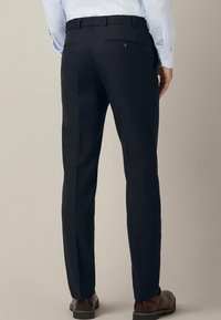 Granatowe spodnie służbowe o dopasowanym kroju, z płaskim przodem, dwiema tylnymi kieszeniami oraz subtelnym detalem w postaci zakładki. Teksturowana tkanina o gładkim wykończeniu.
