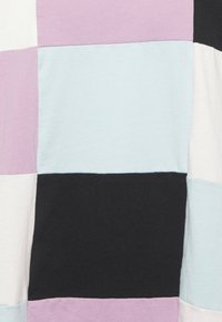 Tecido de patchwork colorido apresentando grandes quadrados em lavanda, azul claro, preto e branco, feito de uma textura suave e macia.