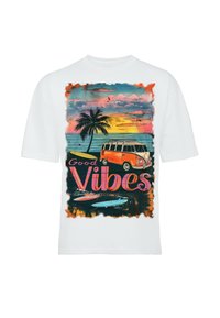 Wit T-shirt met korte mouwen met een kleurrijke afbeelding van een busje, een palmboom en de oceaan, met de tekst "Good Vibes" in vet en speels lettertype.