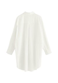 Camisa blanca de manga larga con un acabado texturizado, que presenta un cuello y mangas abotonados, y un espalda ligeramente alargada.