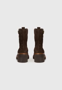 Hnědé semišové kotníkové boty s blokovaným podpatkem, bočním zipem a poutkem na zadní straně; hladká textura s kontrastním prošíváním.