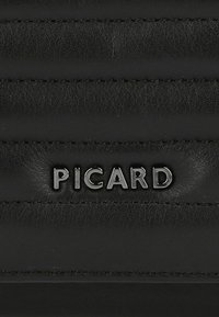 Zwarte leren handtas met verticale gewatteerde textuur; beschikt over een opvallend reliëf "PICARD" logo in zilverkleurige hardware.