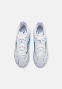Scarpe da calcio sintetiche bianche con dettagli blu, dotate di una superficie testurizzata, punta rotonda e chiusura con lacci. Branding evidente sui lati.