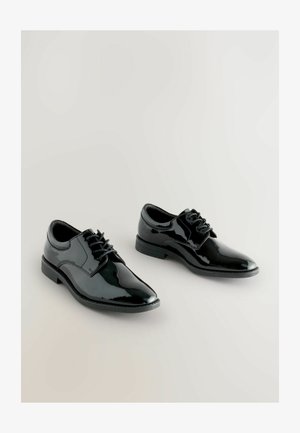 Juodi patentiniai odiniai bateliai su smailiu nosiu, susivyniojimo dizainu ir tekstūruotomis šoninėmis dalimis. Lygus guminis padas, demonstruojantis elegantišką modernų stilių.